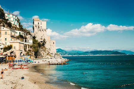 Cetara, Italy - October 2, 2013: Cetara small beach village on the Amalfi Coast, LA beach is defended by an ancient Saracen tower. Bathers on the beach on a warm October day. In the background you can see the city of Salernoのeditorial素材