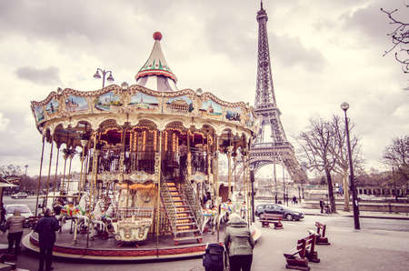 Paris, France - March 18, 2012: Children accompanied by their parents and grandparents play the carousel of the Eiffel Tower in Paris on a wet and cloudy day in Marchのeditorial素材