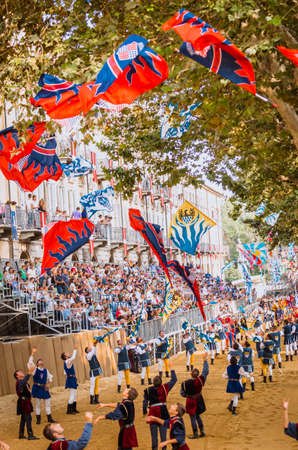 Asti, Italy - September 16, 2012: the historical Medieval parade of the Palio of Asti in Piedmont, Italy. Acrobats of flags perform on the race track of horses, flag-waving parade in medieval Palioのeditorial素材
