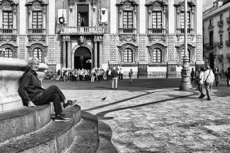 Catania, Italy - October 23, 2015: One Sicilian elderly lonely sitting on the stairs elephant fountain in the square, in the city center of Catania in Sicily, Italyのeditorial素材