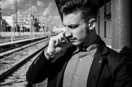 railway station at man with smart phone in hand is waiting for the trainの写真素材