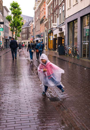 child with his raincoat on pebbles old city in case of rain, the Netherlandsのeditorial素材