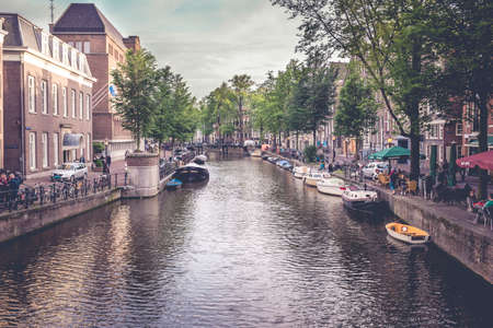 Amsterdam, Netherland - June 15, 2016: view of a canal in Amsterdam the netherlands. quiet urban scene of the city center with people relaxing on the sides of the channel, on a day in early summerのeditorial素材