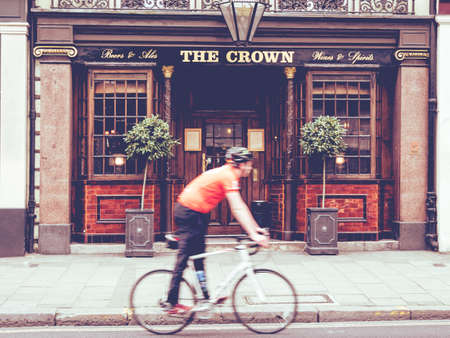 Urban scene of a cyclist walking in front of an English pubのeditorial素材