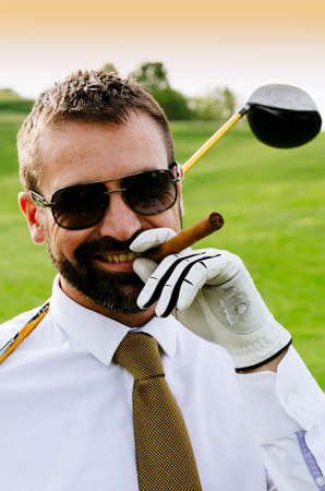 Portrait of smiling golfer with cigar with driverの写真素材