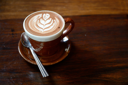 Cup of hot latte art coffee on wooden tableの写真素材