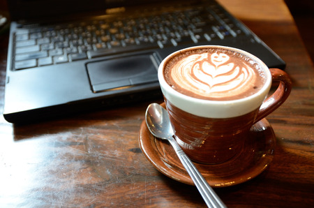 Laptop, notebook and coffee cup on wood deskの写真素材
