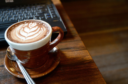 Laptop, notebook and coffee cup on wood deskの写真素材