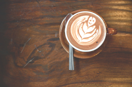 Cup of hot latte art coffee on wooden tableの写真素材