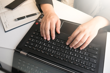 Businesswoman typing on laptop keyboard in officeの写真素材