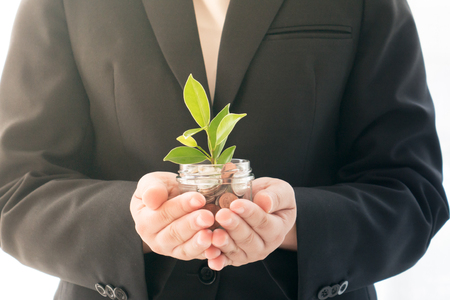 Businesswoman holding cup with coin and tree for business growth conceptの写真素材