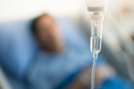 Focus on IV drip chamber with patient in Hospitalの写真素材