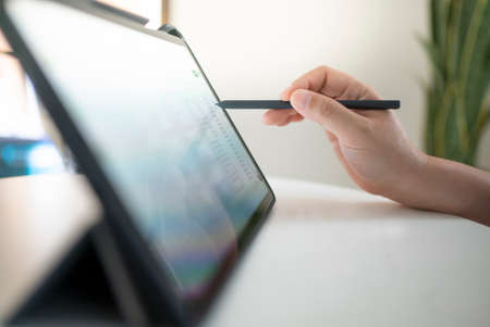 Close-up image of a female hand holding a stylus pen and using a digital tabletの写真素材