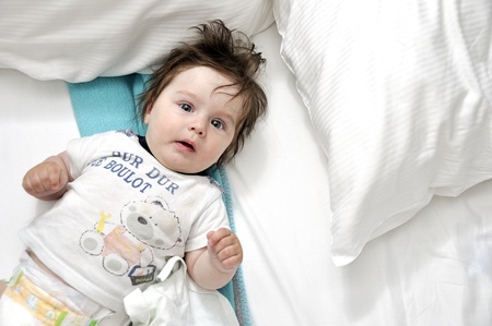 Baby in bed with two pillowsの写真素材