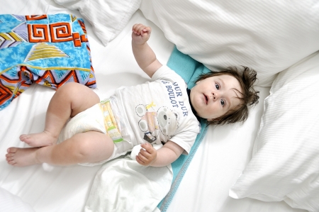 Baby in bed with two pillowsの写真素材
