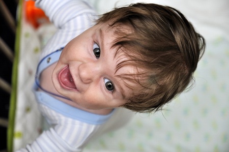 Hairy baby leans on bed and smilesの写真素材