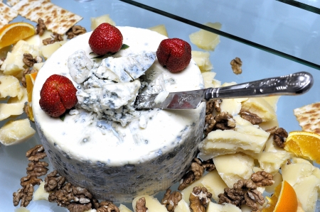 Big cheese with mold with knife inside served by strawberry, orange and nutsの写真素材