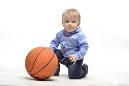 Little boy plays with basketball ball in studioの写真素材