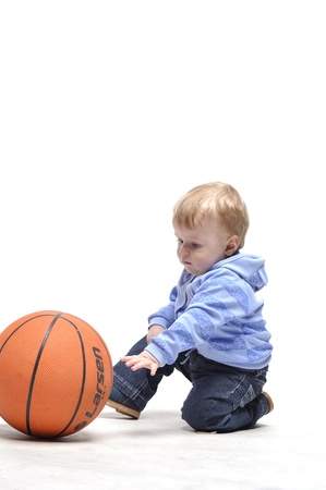 Little boy plays with basketball ball in studioの写真素材