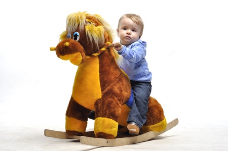 Baby sit on wooden toy horse in studioの写真素材