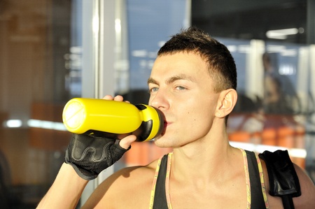 Portrait of the attractive young man in a sunlight drinking waterの写真素材