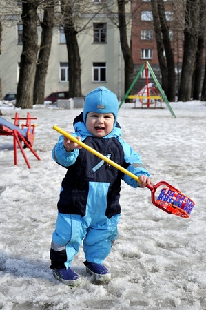 Little boy plays at playground in wintertime with toyの写真素材