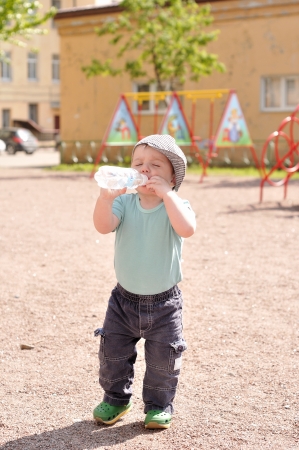 Little boy drinks water from a bottleの写真素材