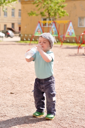 Little boy drinks water from a bottleの写真素材