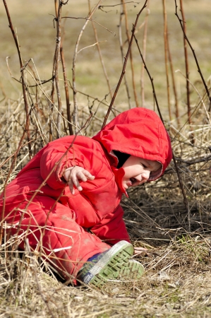 Little boy in red overalls tries to rise from earthの写真素材