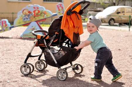 Little boy pushes carriage at playgroundの写真素材