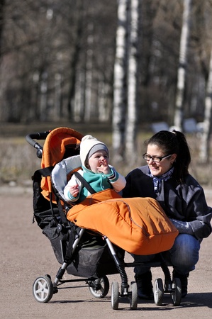 Little child in carriage with mother in city parkの写真素材