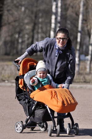 Little child in carriage with mother in city parkの写真素材