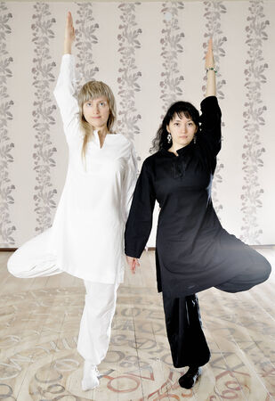 Two young woman black and white dressed doing yogaの写真素材