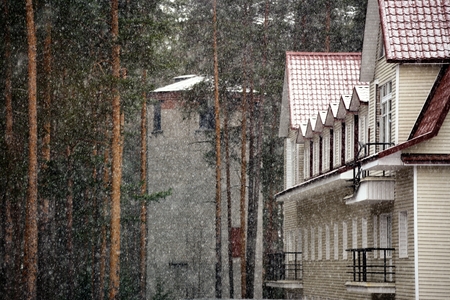 Snowing with view on forest house and towerの写真素材
