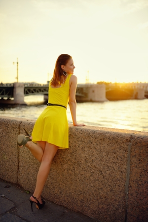 Portrait of the beautiful woman in a yellow dress on the embankment in Sankt Petersburg at sunsetの写真素材