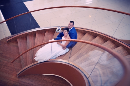 Happy bride and groom on their wedding stand on a wooden ladderの写真素材