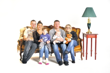 Two young families with a child sit on a sofaの写真素材