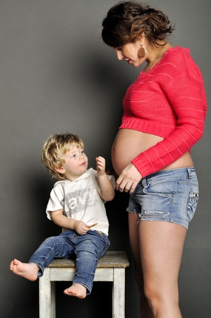 Beautiful pregnant mother with the child in studioの写真素材
