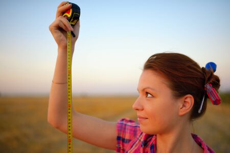 Young woman holds tapeline roulette in a hands at fieldの写真素材