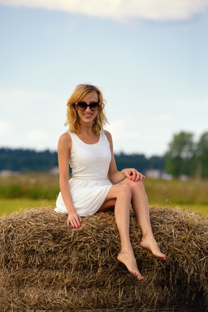 Sexy fashion woman in sunglasses and white dress on haystackの写真素材