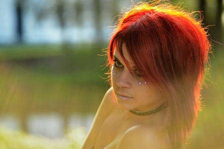 Portrait of beautiful red-hair woman on the natural background with sunshine backlightの写真素材