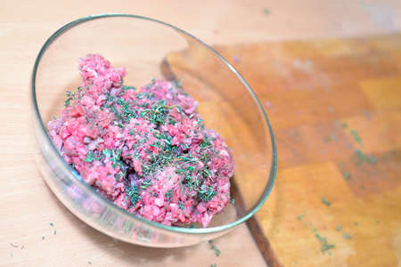 Pieces of fresh beef in a glass bowl near chopping boardの写真素材