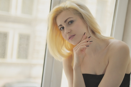Portrait close up of young beautiful blonde woman near windowの写真素材