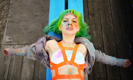 Top view on young girl with green hair lying on benchの写真素材
