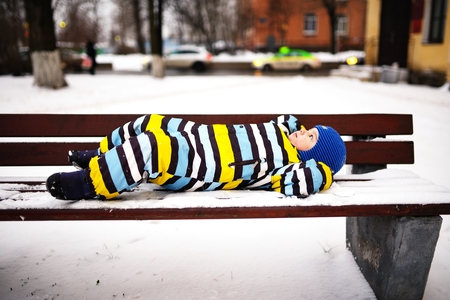 Small child has rest on bench in winterの写真素材