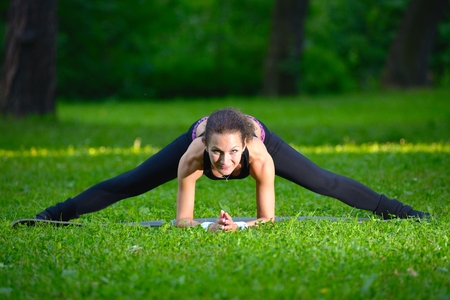 Sports girl does exercises workout outdoors in parkの写真素材
