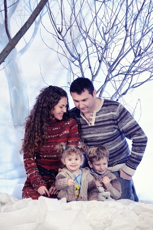 Family portrait sits on studio snow forest backgroundの写真素材