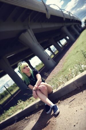 Beautiful young swag woman with green hair posing near highway roadの写真素材