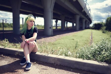 Beautiful young swag woman with green hair posing near highway roadの写真素材