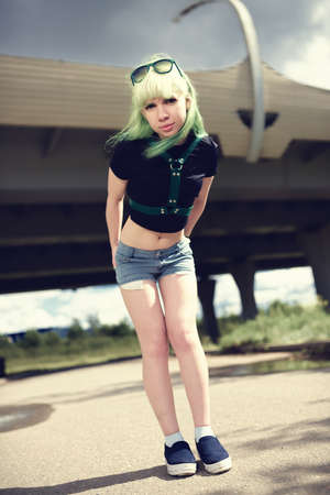 Beautiful young swag woman with green hair posing near highway roadの写真素材